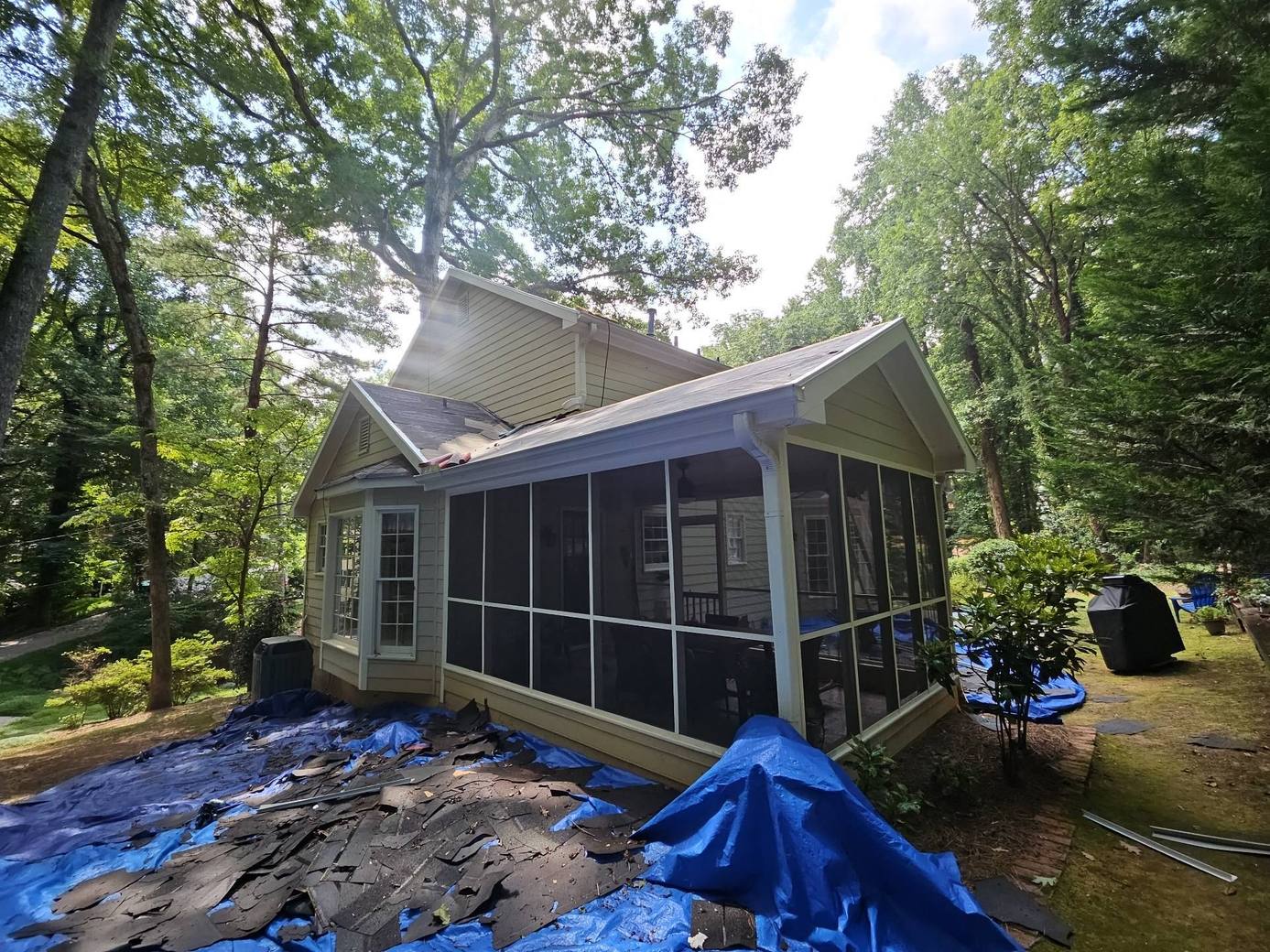 Old shingles torn off and piled on tarps beside the screened porch in Roswell GA