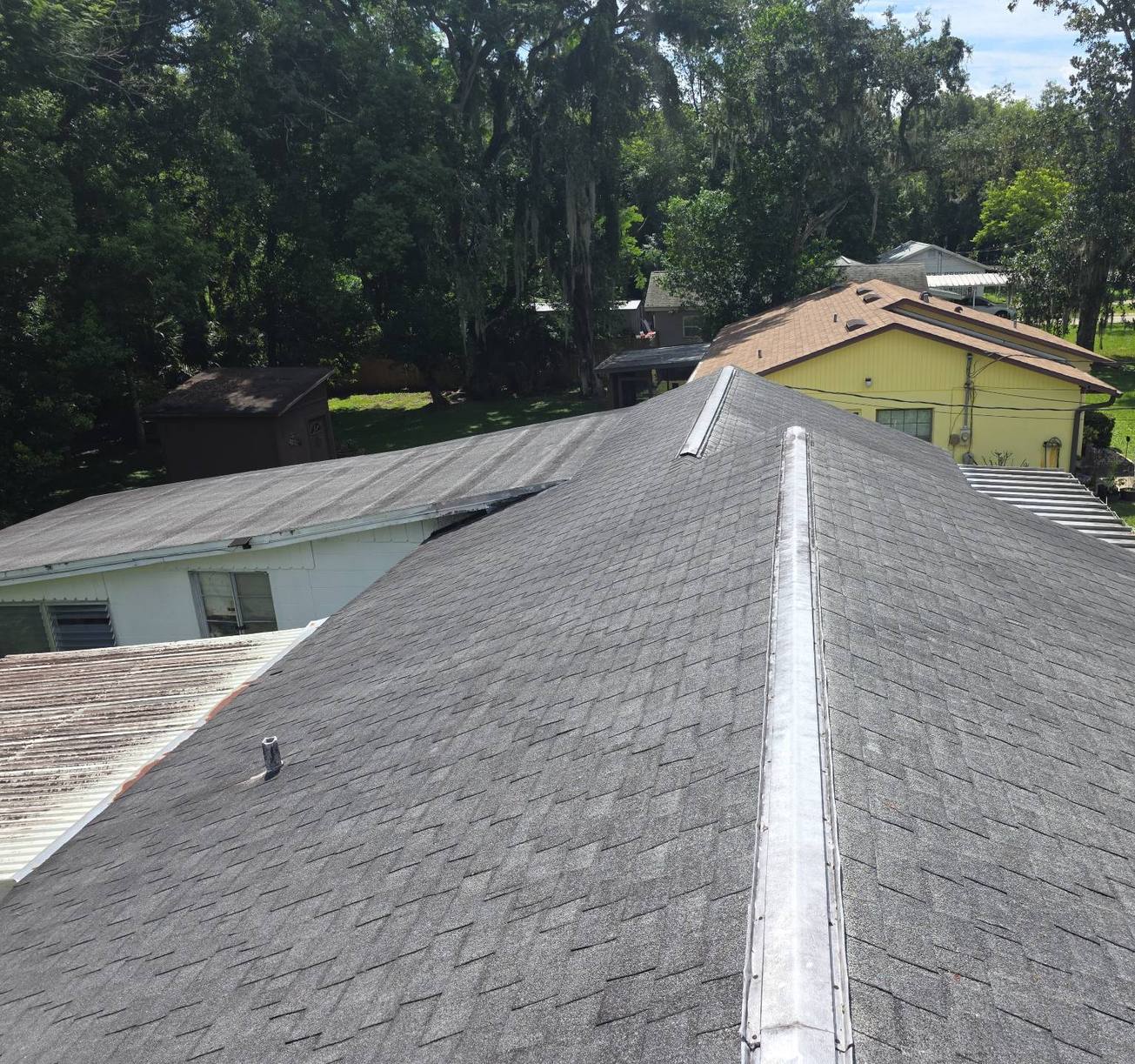 Old shingle ridge and worn metal ridge cap on a DeBary FL roof